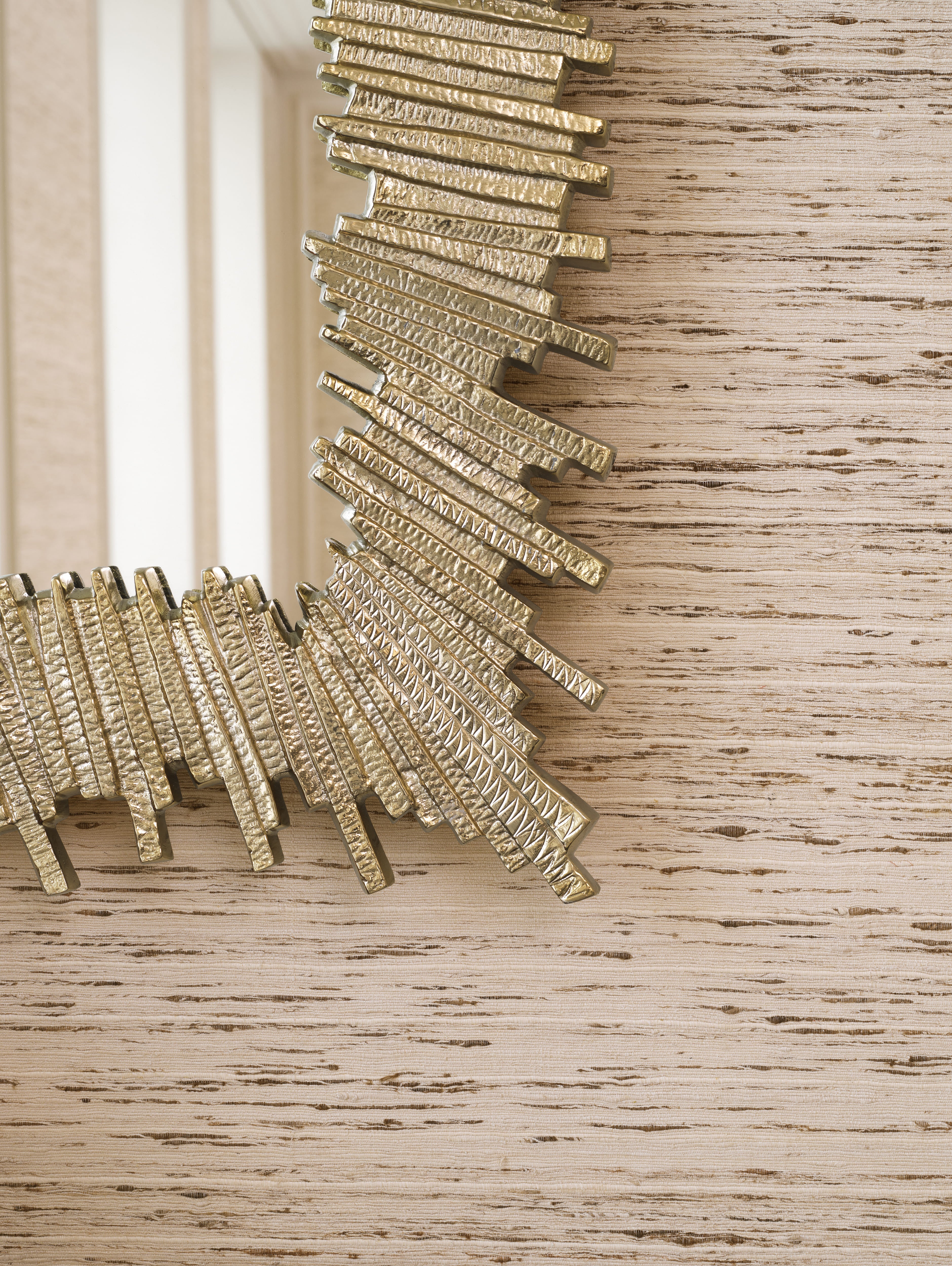 Detailaufnahme eines Eichholtz Spiegels mit strukturierter goldfarbener Oberfläche vor heller Wandgestaltung.