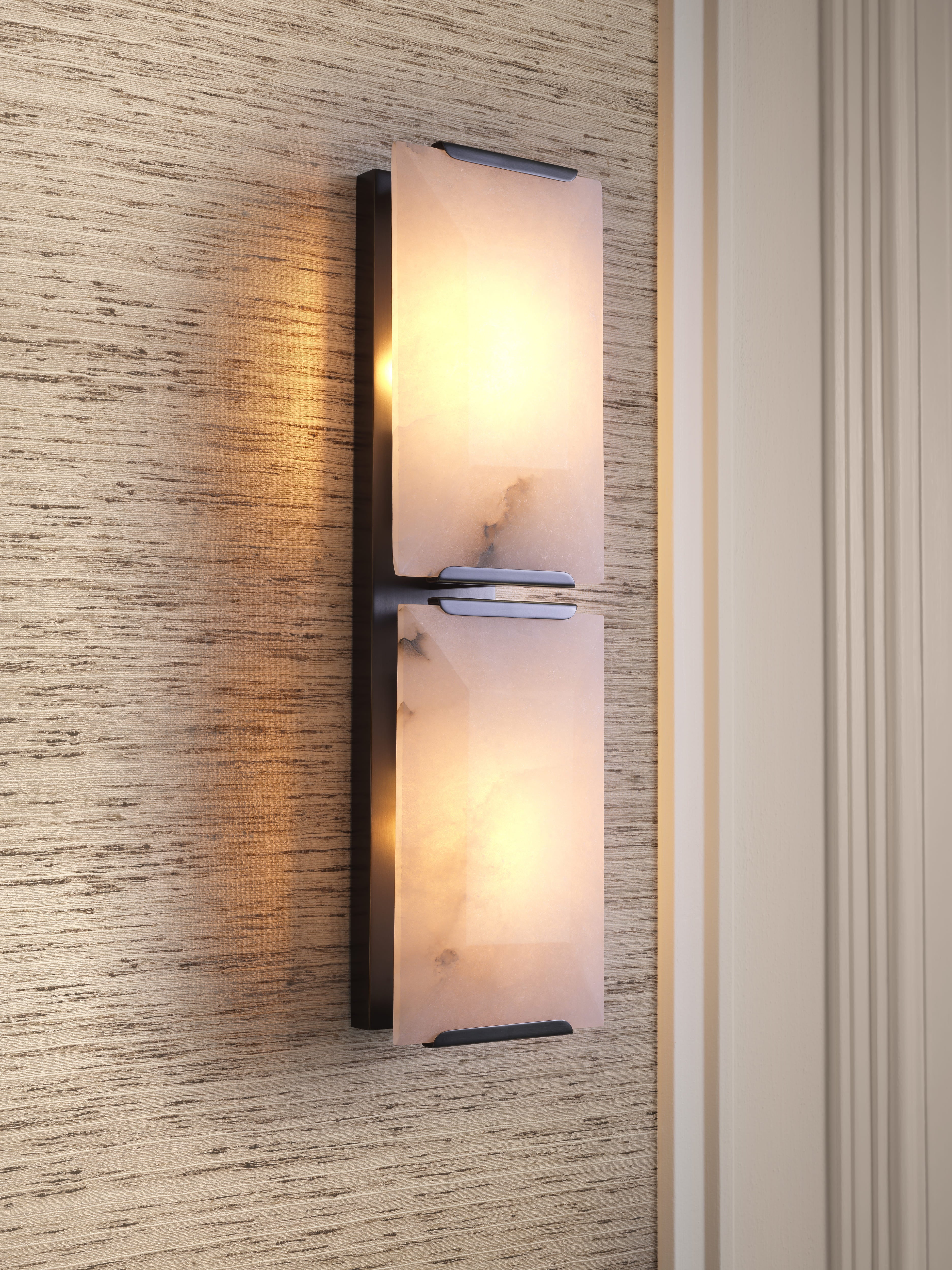 Moderne Eichholtz Wandleuchte mit Natursteinoptik und warmem Licht an eleganter Wandverkleidung.